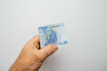 Photo for A hand tightly grips a twenty euros bill, showcasing its value and currency - Royalty Free Image