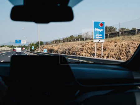 Photo for A defocused view from inside a driving car at the Clinica Balera Hospital direction signage - Royalty Free Image