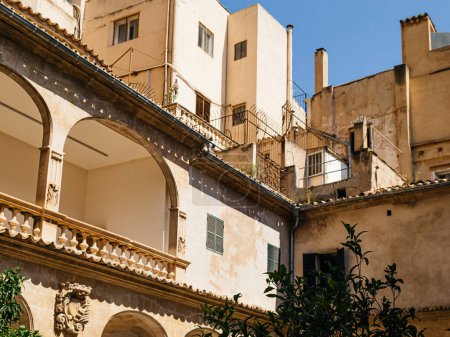Téléchargez les photos : Un grand immeuble à Palma de Majorque, orné de plusieurs colonnes, placé contre un ciel bleu clair, capturé d'un angle bas - en image libre de droit