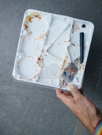 Photo for From a first-person perspective, a man moves towards the kitchen, carrying a tray with a broken spatula and scattered cake crumb - Royalty Free Image