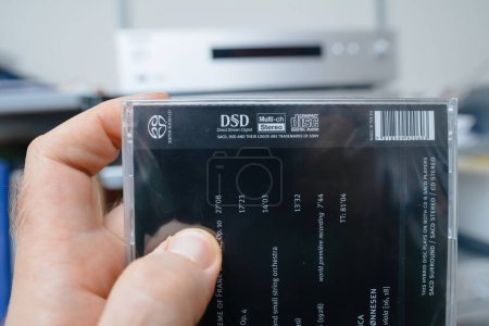 Photo for Paris, France - Dec 28, 2023: male hand, in an audiophiles meticulously designed room, carefully examines the SACD featuring the DSD and Multi-Ch Stereo logos from the BIS label with Benjamin Britten - Royalty Free Image