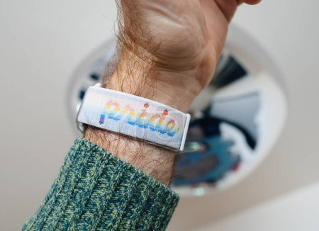 Photo for Bremen, Germany - Dec 28, 2023: A male hand proudly holding an Apple Watch Ultra 2 smartwatch adorned with a Pride wristband featuring a rainbow flag and text, celebrating diversity and inclusivity - Royalty Free Image