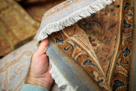 Une personne examine de près les couleurs et la sensation tactile du tapis de laine sur le parquet en bois