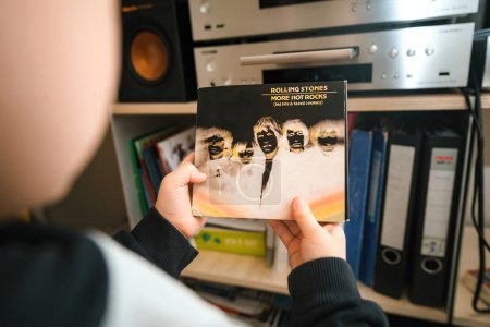 Photo for Paris, France - Jan 18, 2024: A young audiophile explores the More Hot Rocks SACD by the Rolling Stones, while surrounded by a high-end hi-fi system and luxury speakers in a living room, beginning a - Royalty Free Image
