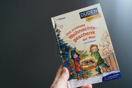 Foto de París, Francia - 18 de enero de 2024: Hombre acaparando a mano el nuevo libro de Duden Leseprofi con el título alemán Das schonste Weihnachtsgeschenk der Welt - Imagen libre de derechos