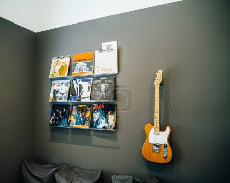 Téléchargez les photos : Lyon, France - 2 juil. 2023 : Un coin cosy dédié à la musique, avec des disques vinyles exposés et une guitare classique prête à être jouée, évoquant une ambiance musicale. - en image libre de droit