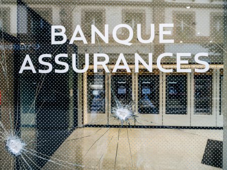 Foto de Sucursal bancaria, con texto en francés Banco y Seguros con su vidrio roto después de una protesta en Francia, destacando las consecuencias de la manifestación - Imagen libre de derechos