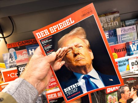 Photo for Berlin, Germany - Jan 25, 2024: POV of a hero object from the latest Der Spiegel German magazine featuring a cover of Donald Trump saluting with the headline Dictator Trump. A male hand shopping for - Royalty Free Image