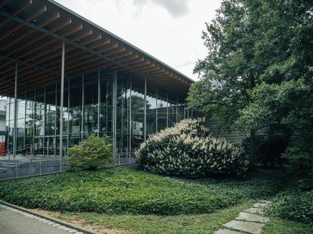 Téléchargez les photos : Rheinau, Allemagne - 2 juil. 2023 : Bâtiment moderne en façade vitrée avec un paysage verdoyant et un ciel couvert. World of Living Afficher la maison centreentrée principale - en image libre de droit