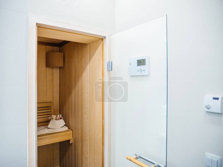 Photo for Compact modern sauna room with a wooden finish and digital control panel. - Royalty Free Image