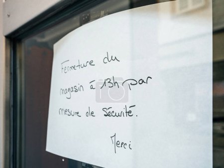 Téléchargez les photos : Panneau manuscrit en français indiquant la fermeture du magasin pour des raisons de sécurité sur la porte vitrée. - en image libre de droit