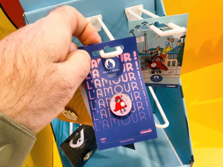 Foto de Mano celebración 2024 París Olympic Phryges Caps pin, comprado en una zona dedicada tienda de ventiladores, destacando la conexión paralímpica. - Imagen libre de derechos