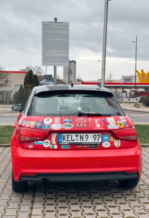 Téléchargez les photos : Kehl, Allemagne - 23 janv.2024 : Vue arrière d'une Audi rouge garée dans un grand parking public en Allemagne, ornée de multiples autocollants de différents pays et de différentes situations, présentant - en image libre de droit