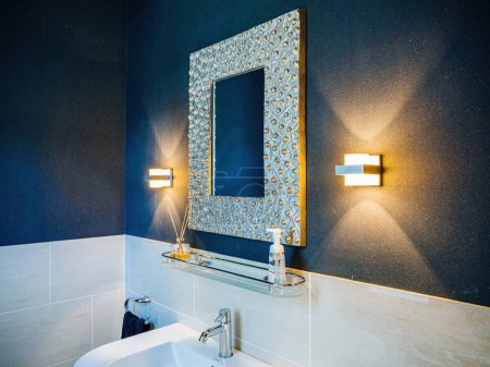 Foto de Elegante baño con espejo de diseño, accesorios de iluminación elegantes y comodidades modernas: interior de lujo - Imagen libre de derechos