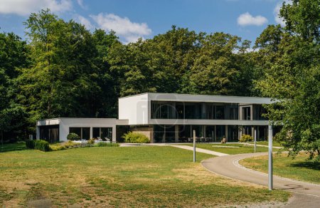 Foto de Villa moderna con fachadas de vidrio y diseño minimalista rodeada de un entorno de parque natural. - Imagen libre de derechos