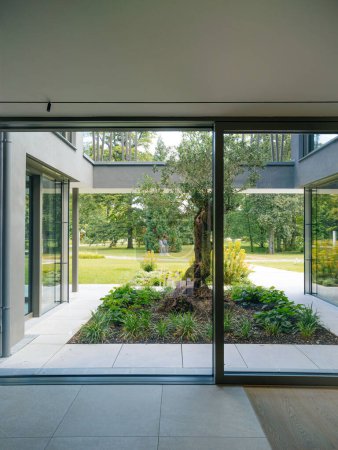Photo for Open glass door of a modern home leading to a beautifully landscaped garden with a pathway. - Royalty Free Image
