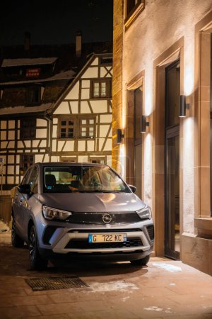 Téléchargez les photos : Strasbourg, France - 23 oct. 2022 : Une voiture électrique Opel élégamment garée devant une luxueuse maison en pierre de Gres des Vosges, nichée au cœur du centre de Strasbourg Petite France - en image libre de droit
