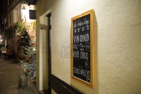 Téléchargez les photos : Strasbourg, France - 19 déc. 2022 : Une charmante scène nocturne sur la rue française à Strasbourg, ornée d'une bannière festive d'un restaurant vendant du vin chaud, la capitale de Noël de Strasbourg - en image libre de droit