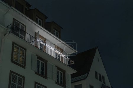 Photo for Low-angle view of a real estate building in France, featuring balconies adorned with charming Christmas lights illuminating the night - Royalty Free Image