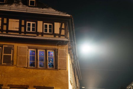 Téléchargez les photos : Nuit festive à Strasbourg : Charmante maison à colombages ornée de lumières de Noël scintillantes, capturée sous un angle bas - en image libre de droit