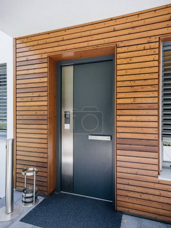 Photo for A modern wooden door with multiple secure points, accompanied by an interphone system and a CCTV camera on the left, exemplifying the security features of this property in the real estate market - Royalty Free Image