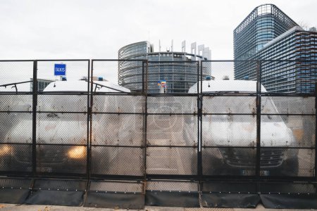 Foto de Estrasburgo, Francia - 6 de febrero de 2024: La policía y las furgonetas militares protegen al Parlamento de los manifestantes con tractores bloqueando la entrada. Protesta contra las normas alimentarias importadas y los nuevos OMG - Imagen libre de derechos