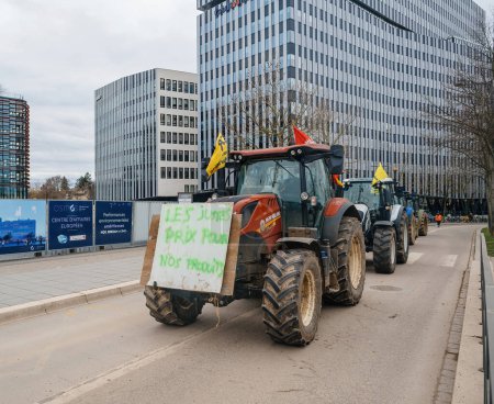Foto de Estrasburgo, Francia - 6 de febrero de 2024: Manifestantes con tractores, portando el mensaje Precio Correcto para Nuestros Productos, bloquean la entrada al Parlamento Europeo, se unen contra alimentos importados con menos - Imagen libre de derechos