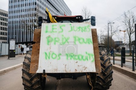 Photo for Strasbourg, France - Feb 6, 2024: A placard reading Correct Prices for Our Products is displayed prominently on a tractor as protesters block the entrance to the European Parliament. - Royalty Free Image