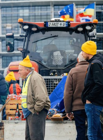 Téléchargez les photos : Strasbourg, France - 6 février 2024 : Un manifestant de haut rang prend les devants alors que des tracteurs bloquent l'entrée au Parlement européen, plaidant contre l'importation de denrées alimentaires de moindre qualité et de nouveaux OGM. - en image libre de droit