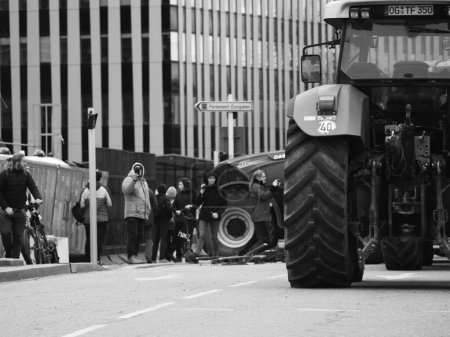 Foto de Estrasburgo, Francia - 6 de febrero de 2024: Manifestantes con tractores bloquean la entrada del Parlamento de la UE mientras el hombre corta paletas para el fuego, protestando contra alimentos importados con estándares más bajos y nuevos OMG. - Imagen libre de derechos