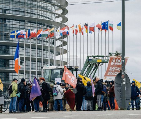 Téléchargez les photos : Strasbourg, France - 6 février 2024 : Une grande foule de manifestants avec des tracteurs bloque l'entrée du Parlement européen - protestation contre les aliments importés avec des normes moins strictes et de nouveaux OGM. - en image libre de droit