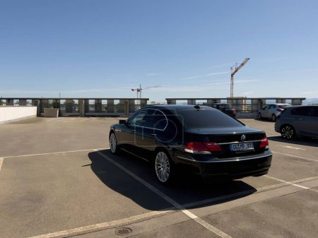 Téléchargez les photos : Francfort, Allemagne - 14 mai 2022 : Vue arrière de la limousine noire de luxe BMW 740iL garée sur le parking sur le toit avec grue en arrière-plan - en image libre de droit