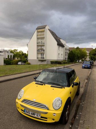 Photo for Strasbourg, France - Sep 10, 2022: Front view of new yellow Mini Cooper car with French real estate apartment building in background - Royalty Free Image