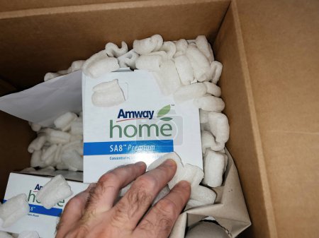 Foto de Paris, France - Sep 12, 2022: Male hand inside the parcel with Amway detergents goods - online e-commerce orders - Imagen libre de derechos
