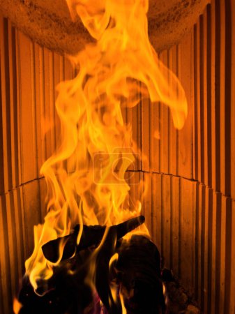 Foto de Una fotografía de cerca que muestra un fuego ardiendo dentro de una estufa de chimenea, emitiendo llamas y luz parpadeante. - Imagen libre de derechos