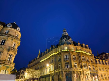 Photo for A very tall Hausmannian building with Christmas decorations displayed prominently on its upper baclony, capturing the urban landscape for the winter holidays - Royalty Free Image