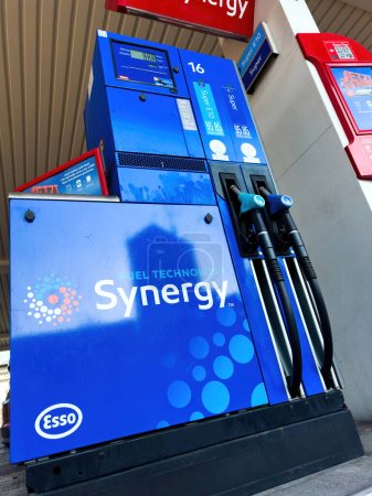 Foto de Una bomba de gas Esso Synergy azul se sienta junto a una gasolinera, lista para suministrar combustible a los vehículos. - Imagen libre de derechos