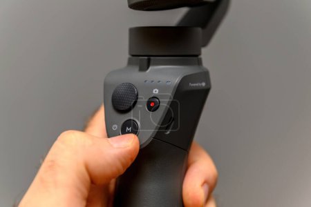 Photo for Paris, France - Aug 16, 2019: A male hand elegantly holds the new DJI Osmo mobile phone gimbal, a versatile tool for stabilizing videos and photos, also functioning as a selfie stick for capturing - Royalty Free Image