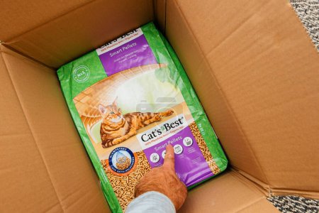 Photo for Bremen, Germany Dec 10, 2023: Unboxing Cats Best Smart Pellets: Male hand points to the words on the cardboard packaging, revealing the innovative litter solution for cats - Royalty Free Image