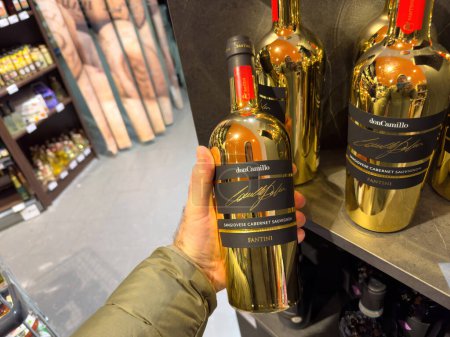 Foto de París, Francia - 21 de diciembre de 2023: la mano masculina sostiene delicadamente una botella de vino Don Camillo Sangiovese Cabernet Sauvignon, presentada en una botella Godel distintiva, perfecta para ocasiones especiales y - Imagen libre de derechos