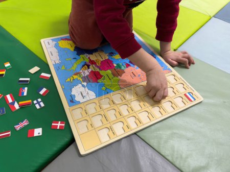 inquisitive nature of a three-year-old toddler as heeagerly engage in assembling a puzzle featuring flags from all countries, fostering early curiosity and learning