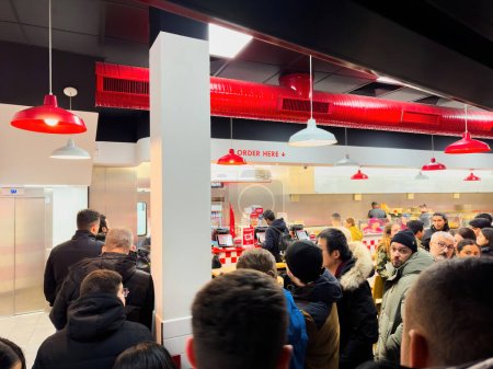 Photo for Strasbourg, France - Dec 25, 2023: bustling scene inside Five Guys fast food as adults and young people eagerly wait to enjoy the iconic American cuisine during the festive Christmas evening. - Royalty Free Image