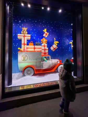 Photo for Strasbourg, France - Dec 25, 2023: toddler marvels at the Louis Vuitton showcase while shopping for Christmas gifts, enchanted by the festive car decorations, creating cherished holiday memories - Royalty Free Image