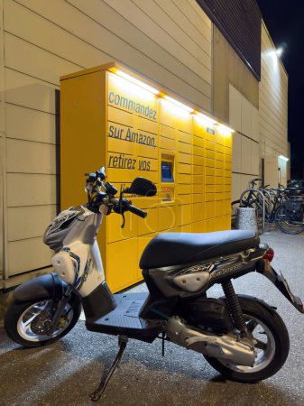 Photo for Lyon, France - Dec 27, 2023: A nighttime view of an Amazon locker illuminated in the dark, with a parked moped positioned in front - Royalty Free Image