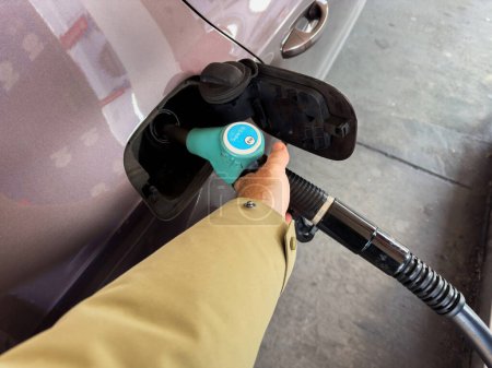Photo for Experience the perspective of a male hand holding the gas pump at the gas station, filling the car with fresh gasoline for a smooth and efficient refueling process. - Royalty Free Image