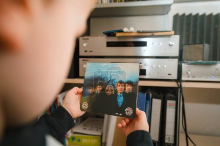 Photo for Paris, France - Jan 17, 2024: A luxurious scene where a toddler holds the SACD format of The Rolling Stones Between the Buttons, with a high-end audio system in the background, depicting early - Royalty Free Image