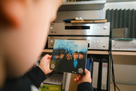 Photo for Paris, France - Jan 17, 2024: A scene featuring a toddler holding The Rolling Stones album Between the Buttons in SACD format, with a luxurious high-end audio system in the background. - Royalty Free Image