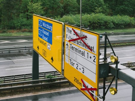 Téléchargez les photos : Panneau jaune vif monté sur un poteau au bord d'une route, fournissant des informations importantes pour les conducteurs et les piétons près de l'aéroport de Francfort - vue en palier - en image libre de droit