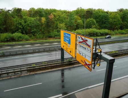 Aerial view of an overhead autobahn direction signage featuring cities like Urzburg Kassel, Basel, and Frankfurt, with Terminals 1 and 2 open, offering a clear guide for travelers on the road