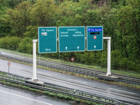 Photo for Aerial view of a direction sign above the German Autobahn, guiding travelers to destinations such as The Squaire, Terminal 1 arrivals, and departures, ensuring smooth navigation for motorists 70 kmh - Royalty Free Image